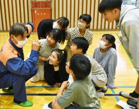 光を当てたときの瞳孔の動きを見せる消防隊員と、興味津々な児童（和歌山県田辺市南新万で）