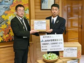 前田敦司龍神行政局長（左）に梅干しを手渡す、ＪＡ紀州の本谷昌平常務理事＝和歌山県田辺市龍神村西で