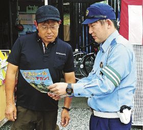 田辺署員から啓発チラシの説明を受ける、マエダ自転車店の前田孝雄さん（左）＝１０月３１日、和歌山県田辺市上万呂で