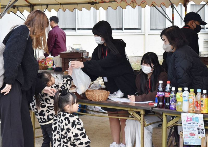 実行委員会の出店ブースで、客に商品を手渡す上富田中学校の生徒（８日、和歌山県上富田町岩田で）