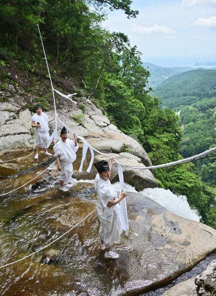 例大祭を前に那智の滝にかかる大しめ縄を新調する神職ら（9日、和歌山県那智勝浦町で）