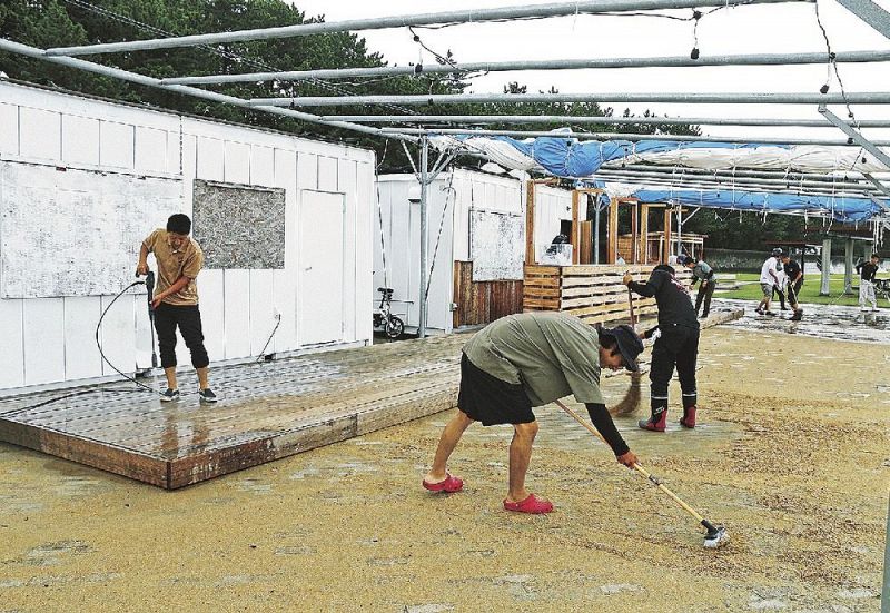 海の家周辺で砂の撤去作業をする関係者ら（１６日、和歌山県田辺市の扇ケ浜海水浴場で）