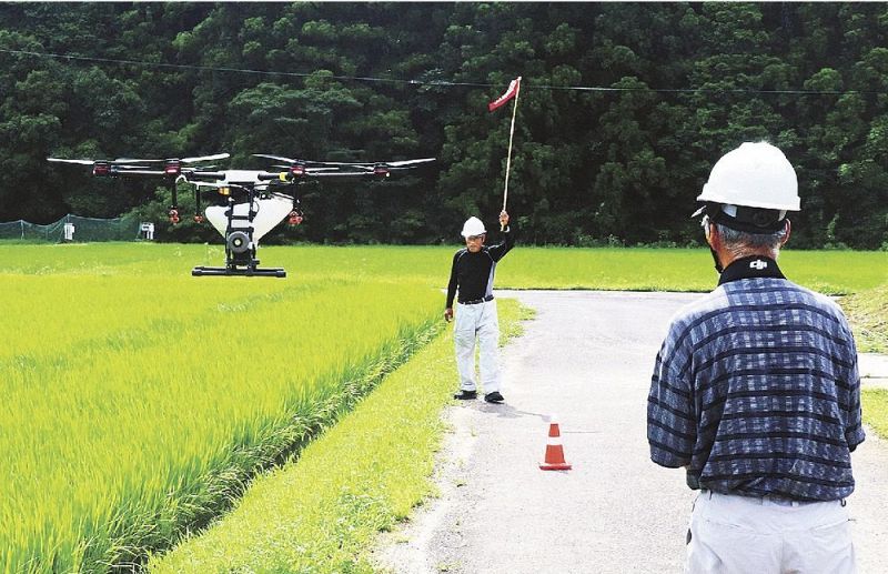 農業用ドローンで田んぼに農薬を散布する鈴木隆文さん（右）と青木一郎さん＝和歌山県白浜町内ノ川で