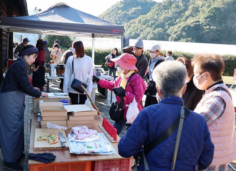 窯で焼いた「紀州備長炭ピザ」を買い求める来場者（１日、和歌山県田辺市秋津川で）