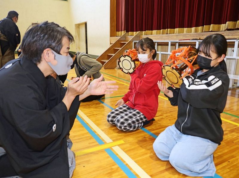 能楽師の指導を受けて、小鼓の演奏を体験する児童（和歌山県田辺市東陽で）