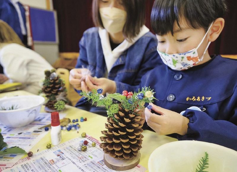 松ぼっくりを自然の素材で飾り付ける園児（和歌山県田辺市上秋津で）