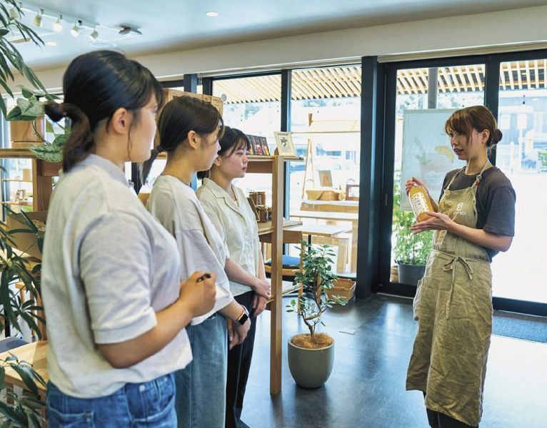 田辺エンプラスで職員（右）から紀南の物語性のある商品について説明を受ける和歌山大学の学生＝和歌山県田辺市湊で