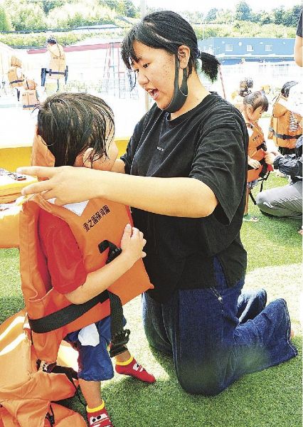 園児にライフジャケットを着せる山口夏姫さん（右）＝和歌山県みなべ町南道で