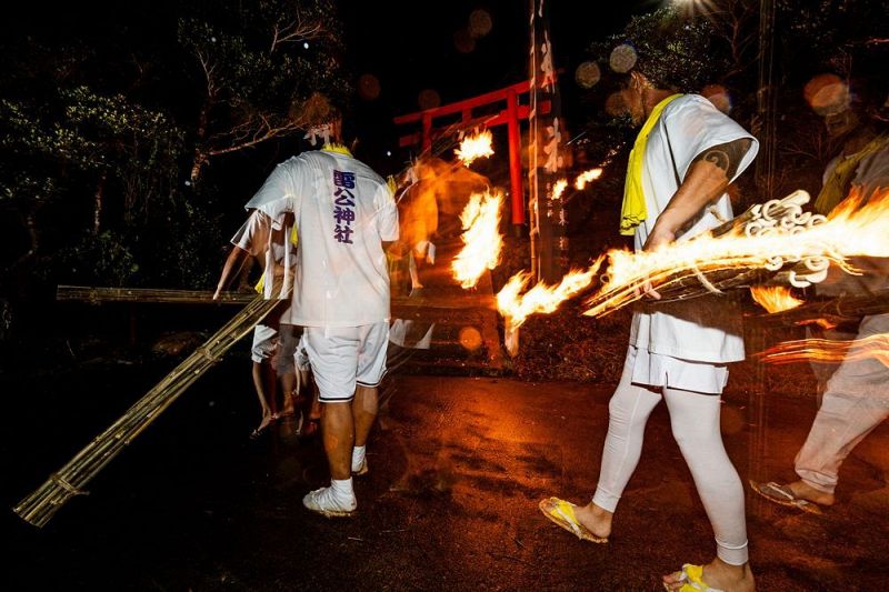 火の付いたたいまつを持ち、階段を駆け上がる若者ら（８日、和歌山県串本町樫野で）