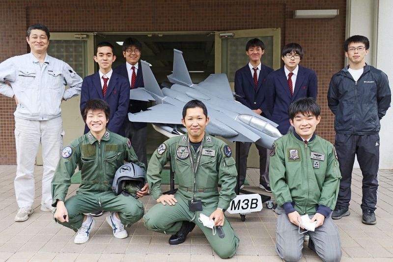 航空自衛官パイロットの飯宮圭祐さん（中央）と「Ｆ１５」の模型を囲んで記念撮影をする田辺工業高校機械科の生徒と教員＝和歌山県田辺市あけぼので