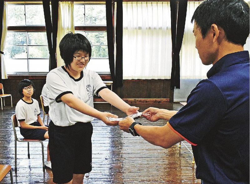 田辺消防署員から梅干しなどを受け取る秋津川中学校の生徒（和歌山県田辺市秋津川で）