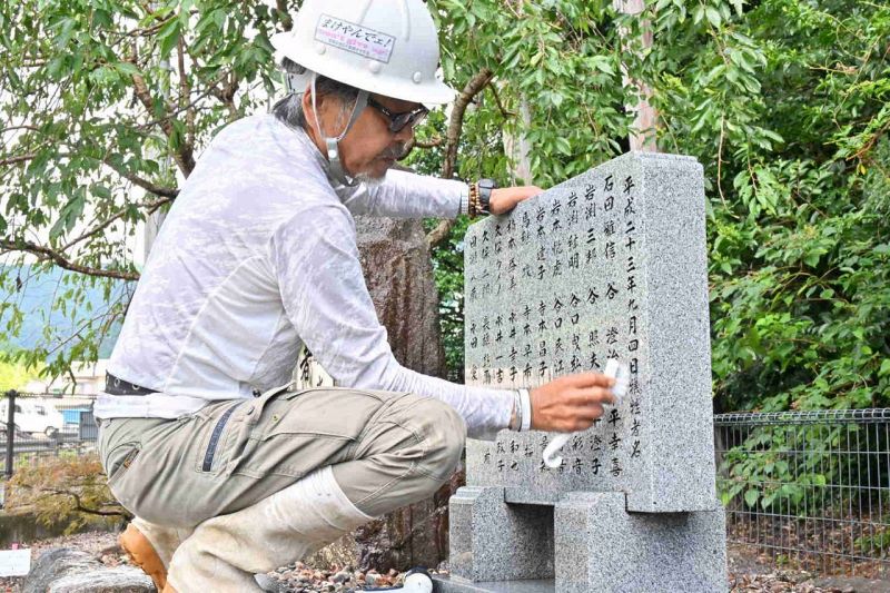 紀伊半島大水害から１２年を前に、犠牲者の名前が刻まれた石碑を丁寧に磨く遺族会の岩渕三千生代表（２６日、和歌山県那智勝浦町で）