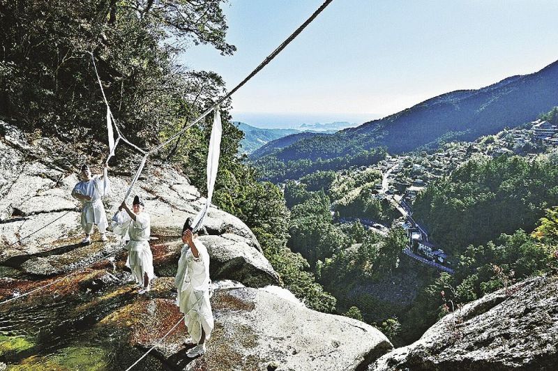 那智の滝の上に架かる大しめ縄を張り替える神職（２７日、和歌山県那智勝浦町那智山で）