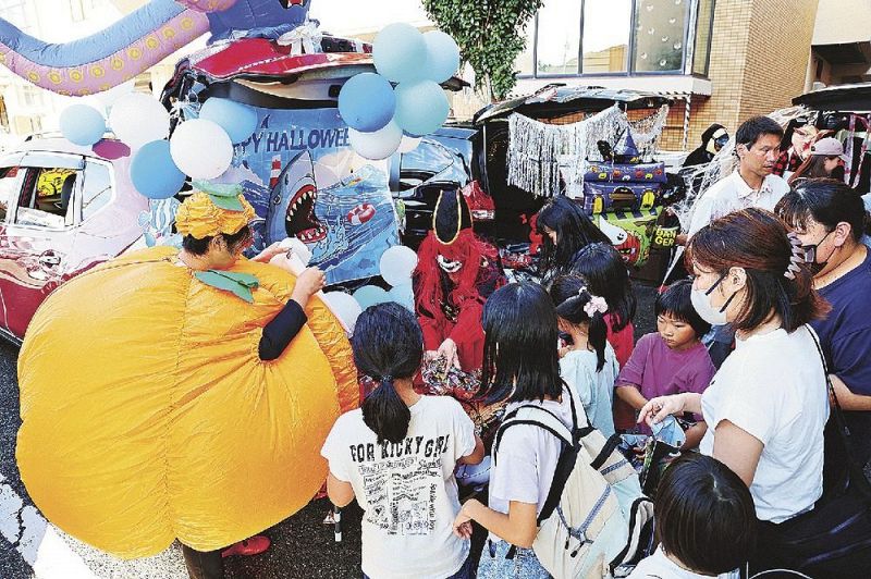 仮装した車から菓子を配る関係者